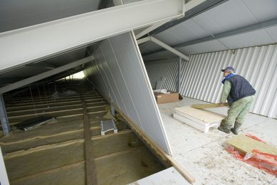 A pig producer insulating part of the roof of his pig house. - Photo: Koos Groenewold