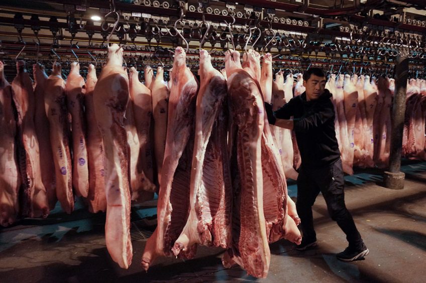 A Chinese worker pushes carcasses in a pork wholesale hall of a market in Beijing, China. Photo: ANP/EPA/Wu Hong