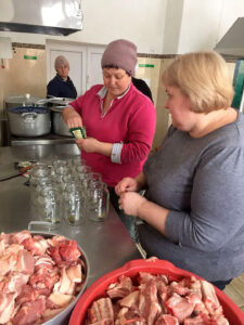 Local villagers process the pork from the farm into food for the Ukrainian soldiers.